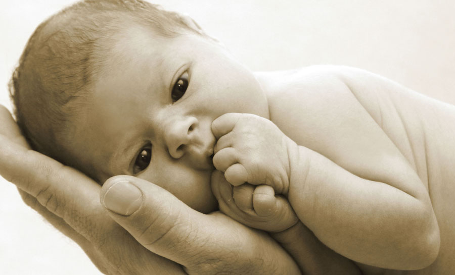 mit offenen Augen liegt das kleine Mädchen auf der Hand seines Vaters