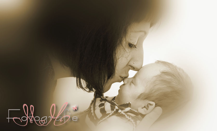 Die liebe Mami gibt ihrem kleinen Mädchen ein Küßchen auf die Nase. Fotographie in sepia
