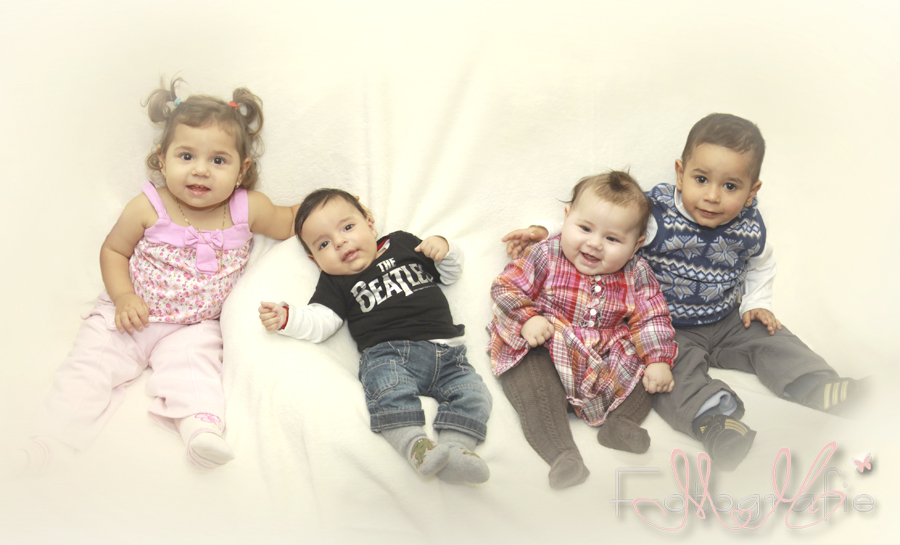 Fotografie von vier Kindern,die auf einer weißen Couch sitzen und fröhlich lachen.