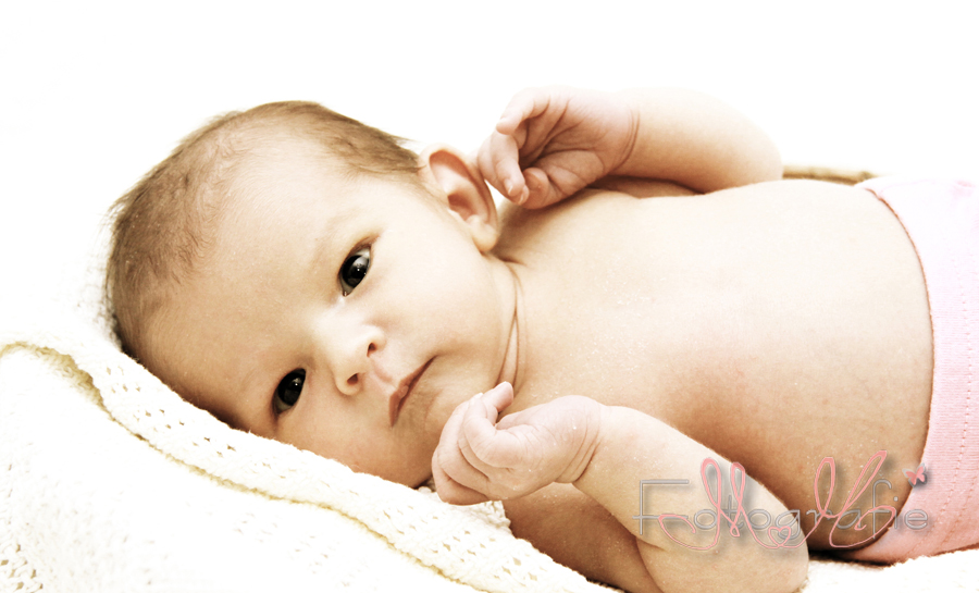 Portraitaufnahme eines nackten kleinen Babys, es schaut mit wachen Augen in die Kamera,