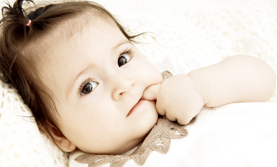 Baby steckt einen Finger in den Mund.