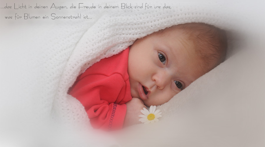Neugierig schaut das kleine Baby unter der Decke hervor