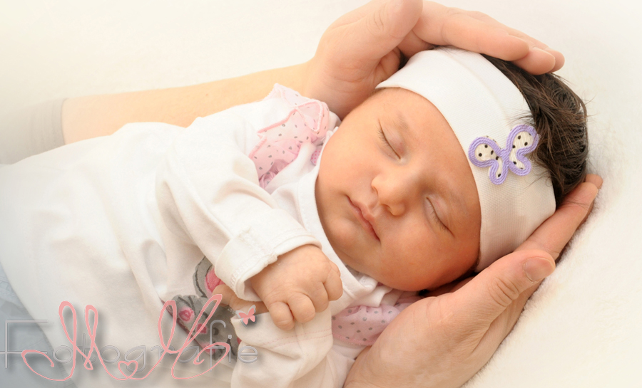 Kleines Mädchen mit einem Stirnband in den Händen seiner Mama