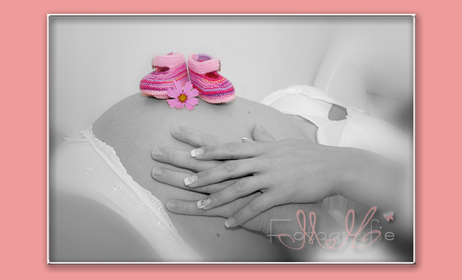 Baby-Bauch-Foto in schwarz-weiß, die Schühchen und die Blume sind farbig gelassen worden.