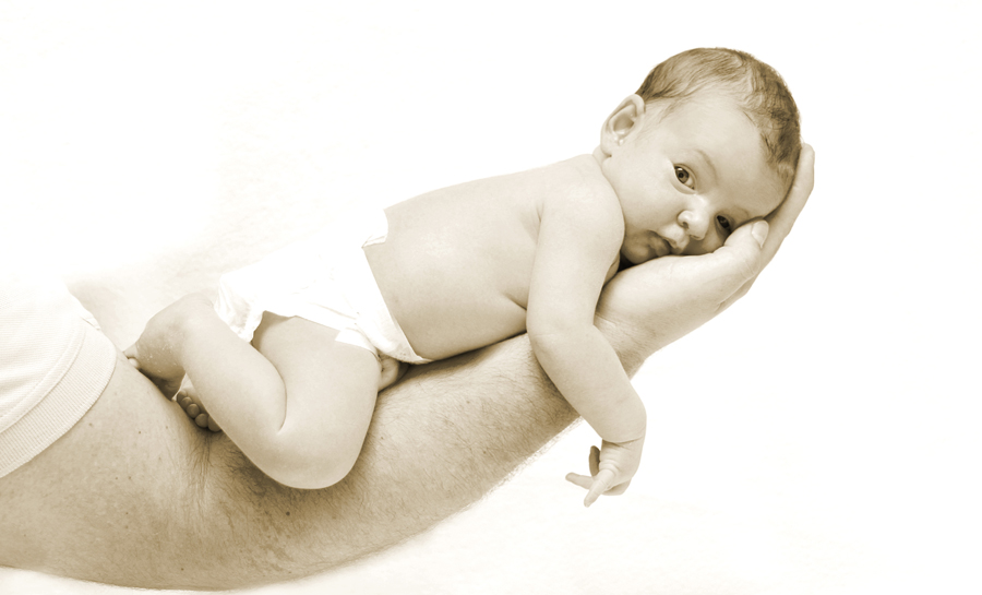 Baby liegt auf dem Arm seines Vaters