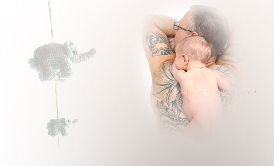 Auf dem Rücken des Vaters liegt sein neugeborenes Baby - ein kleiner Junge