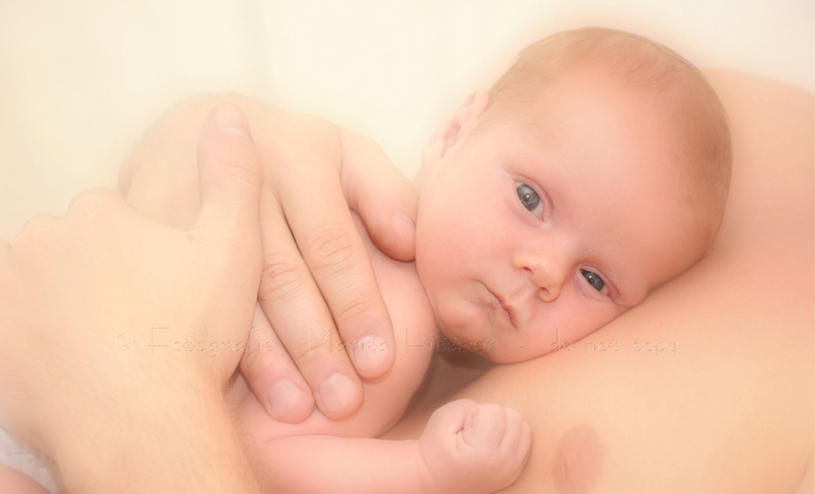 neugeborenes Baby mit offenen Augen auf dem Bauch seines Vaters