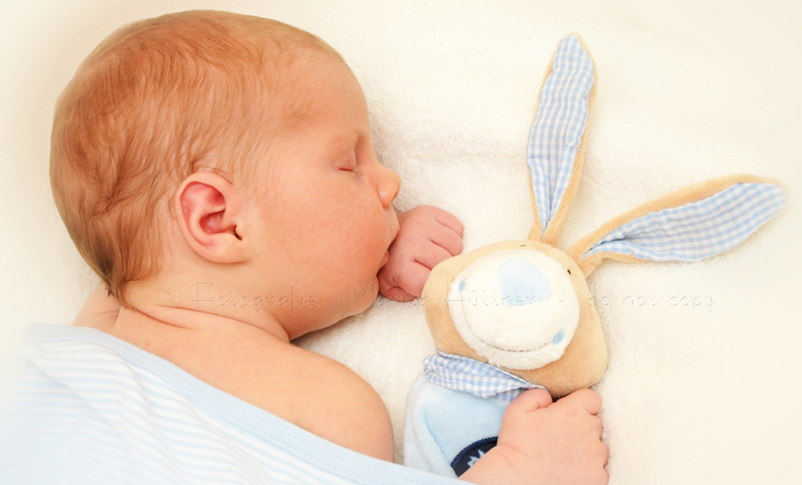 neugeborener kleiner Junge mit Kuscheltier