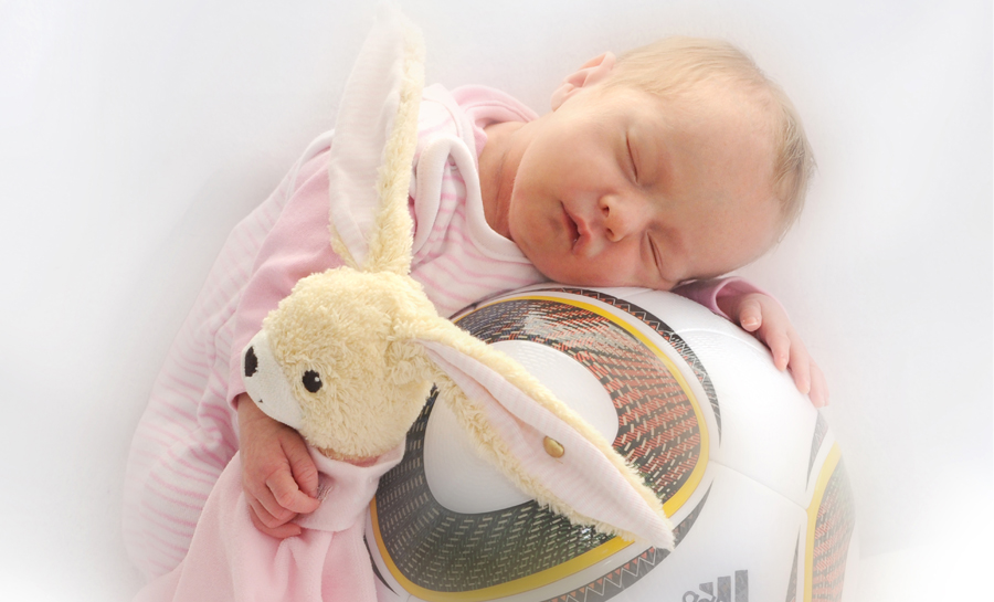 Ein schlafendes Baby, ein Fußball und ein Kuscheltier