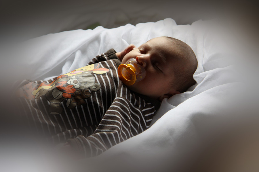 Das kleine Baby liegt in seinem Körbchen und träumt.